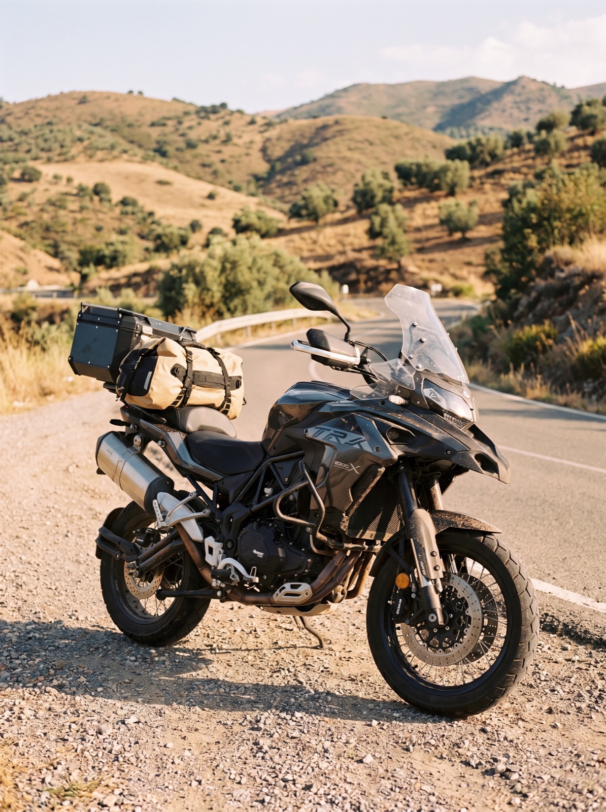 Bepackte anthrazitfarbene Benelli TRK 502X mit Topcase und Gepäckrolle am Rand einer staubigen Piste